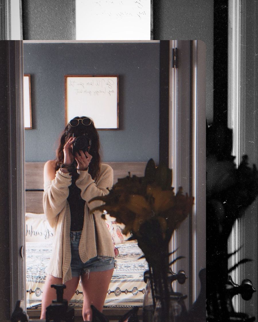 Kaylie Michelle holding a camera while photographing her reflection in a mirror